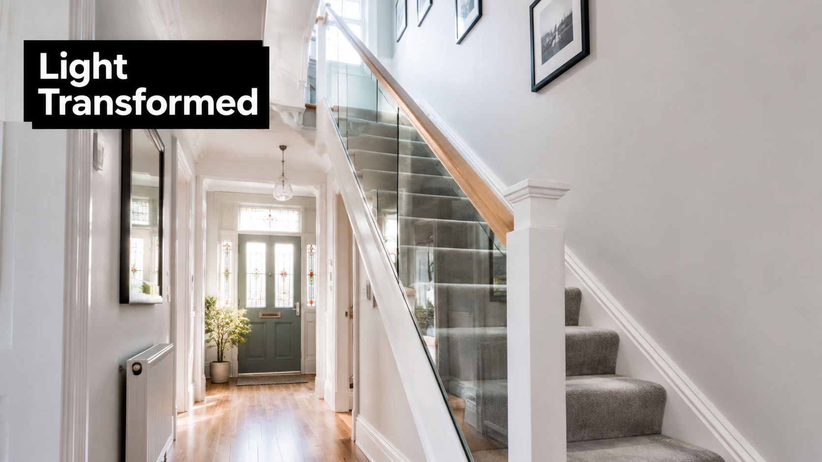 A bright hallway featuring a modern staircase with elegant glass balustrades and grey carpeted steps.